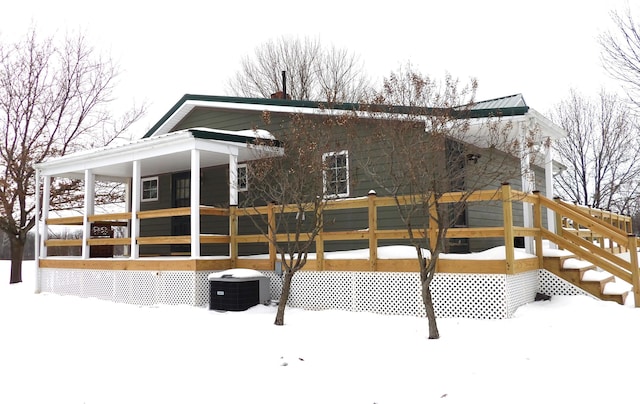 snow covered house featuring central AC unit