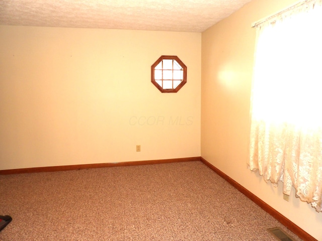 carpeted empty room with a textured ceiling