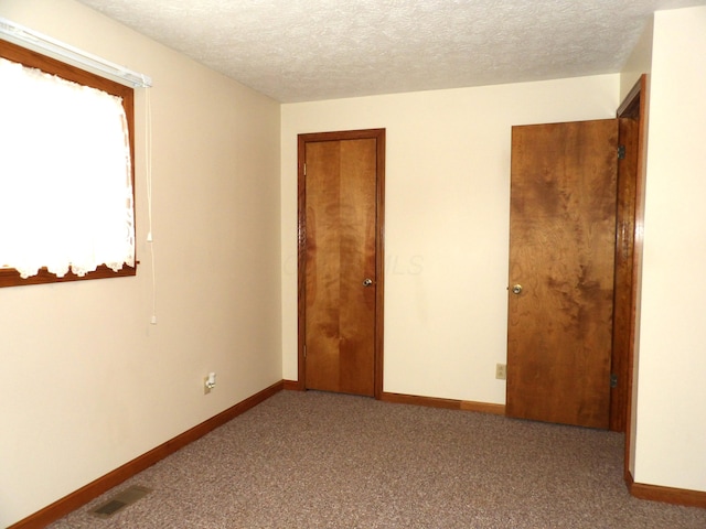 unfurnished room featuring a textured ceiling and carpet floors