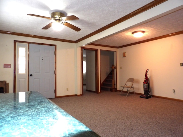 interior space with ceiling fan, carpet flooring, ornamental molding, and a textured ceiling