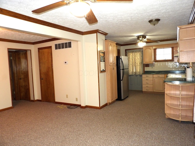 kitchen with light brown cabinets, a textured ceiling, ornamental molding, decorative backsplash, and stainless steel refrigerator