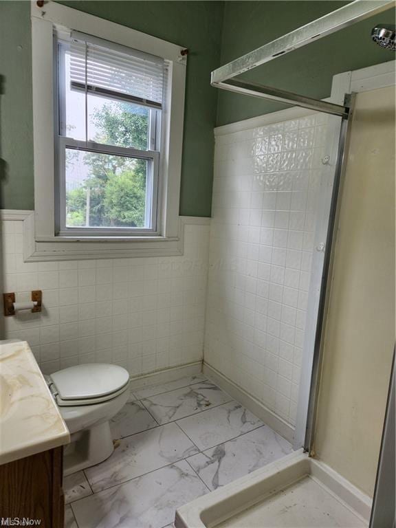 bathroom with walk in shower, vanity, toilet, and tile walls