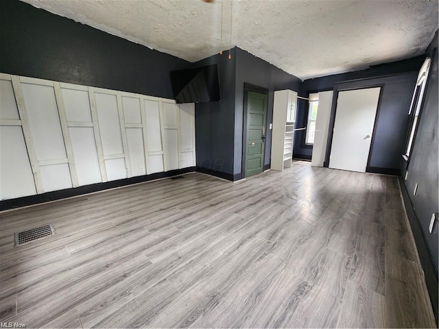 interior space with a textured ceiling and light hardwood / wood-style floors