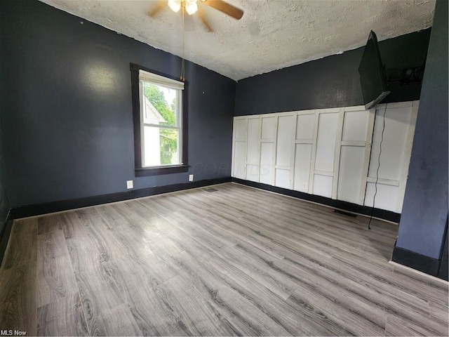 unfurnished bedroom with light wood-type flooring, ceiling fan, and a textured ceiling