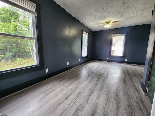 empty room with light hardwood / wood-style floors, a textured ceiling, and ceiling fan