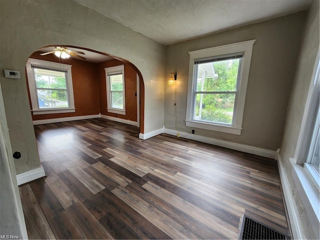 empty room with ceiling fan, dark hardwood / wood-style floors, and a textured ceiling