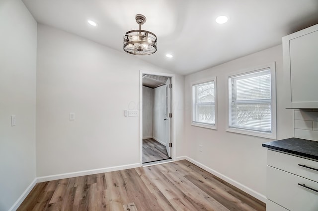 unfurnished dining area featuring lofted ceiling and light hardwood / wood-style floors