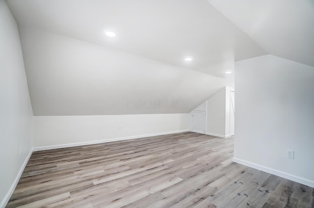 additional living space featuring light hardwood / wood-style flooring and vaulted ceiling