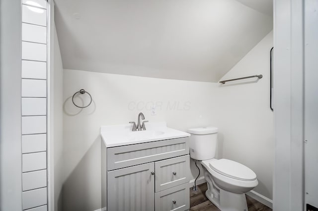 bathroom with lofted ceiling, vanity, wood-type flooring, and toilet