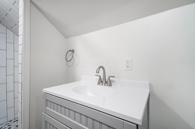 bathroom featuring vanity, lofted ceiling, and a tile shower