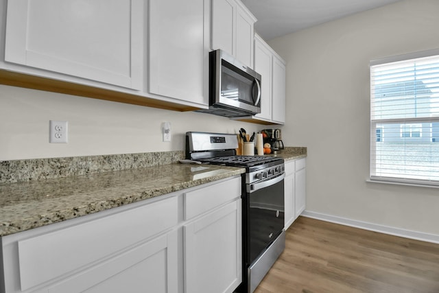 kitchen featuring light stone counters, white cabinets, a healthy amount of sunlight, and appliances with stainless steel finishes