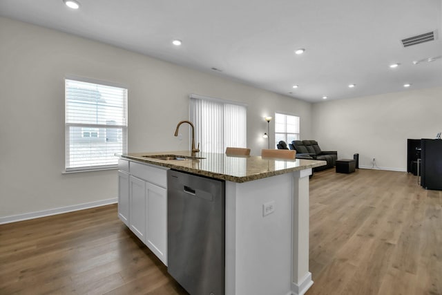 kitchen featuring dishwasher, sink, white cabinets, a kitchen island with sink, and stone counters