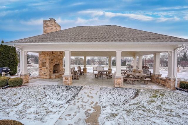 snow covered patio featuring a gazebo, an outdoor stone fireplace, and a grill