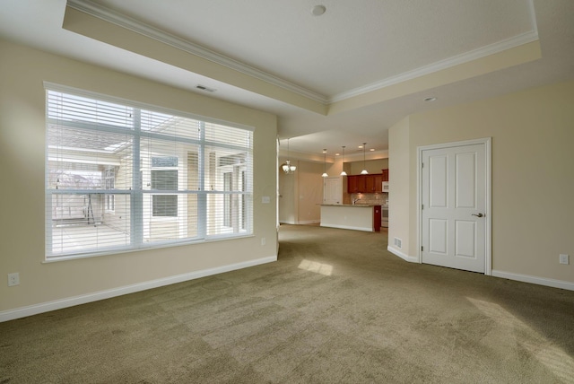 unfurnished living room with dark carpet, ornamental molding, and a tray ceiling