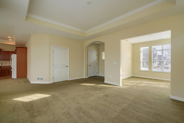 carpeted empty room with a raised ceiling and crown molding