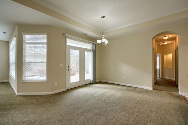 interior space with carpet floors, a raised ceiling, ornamental molding, and a notable chandelier