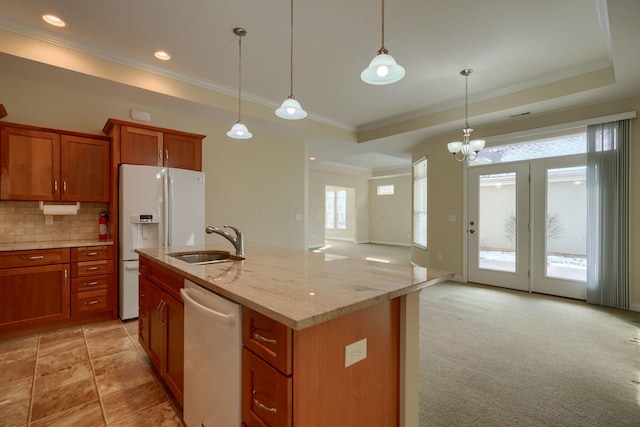 kitchen with a raised ceiling, sink, light colored carpet, white appliances, and a kitchen island with sink