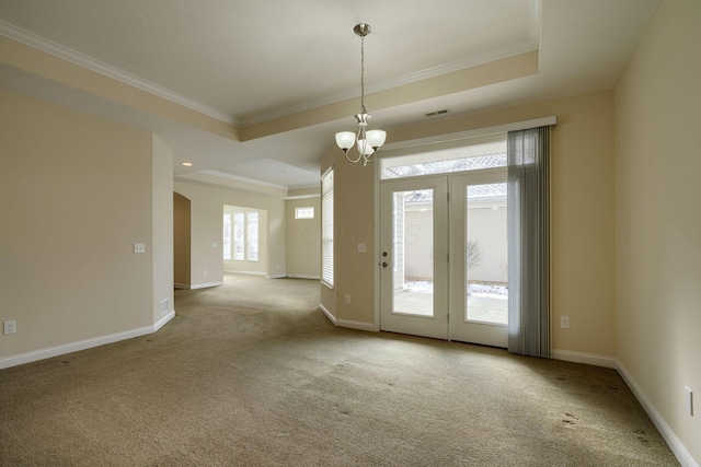 carpeted empty room featuring crown molding, an inviting chandelier, and a raised ceiling