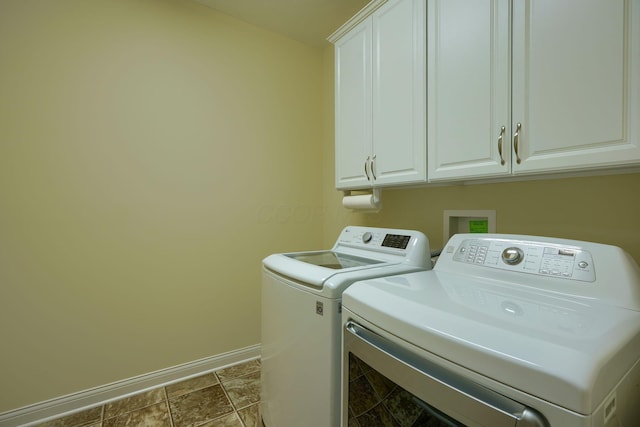 clothes washing area featuring cabinets and separate washer and dryer