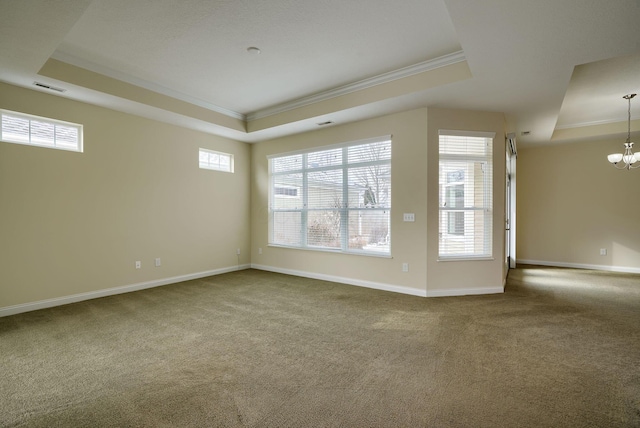 empty room with a chandelier, a raised ceiling, ornamental molding, and carpet flooring