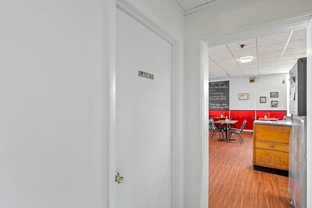 hall with hardwood / wood-style flooring and a drop ceiling