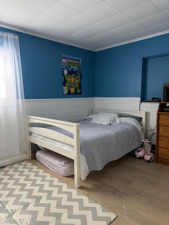 bedroom with hardwood / wood-style floors and ornamental molding