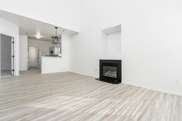 unfurnished living room with a tiled fireplace and light hardwood / wood-style floors