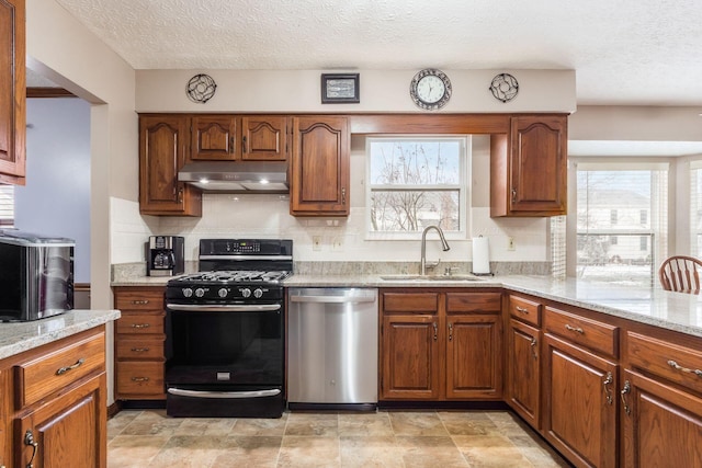 kitchen featuring light stone countertops, sink, dishwasher, and gas stove