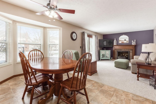 carpeted dining space featuring ceiling fan, a textured ceiling, and a fireplace