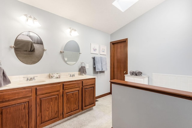 bathroom featuring vaulted ceiling with skylight and vanity