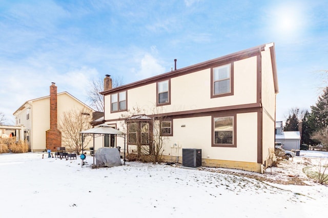 snow covered back of property with cooling unit and a gazebo