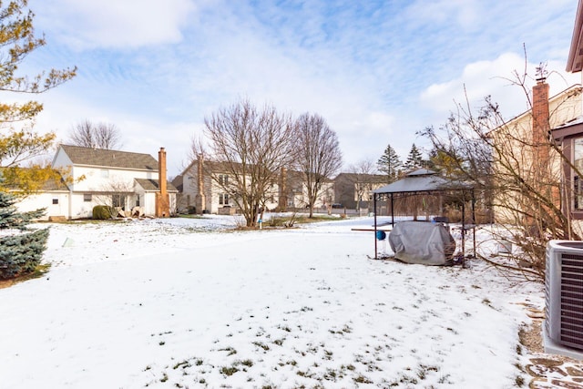 snowy yard featuring a gazebo and central AC