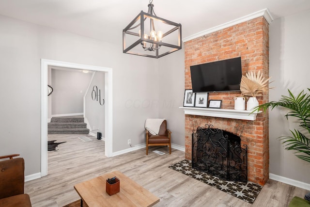 living room featuring light hardwood / wood-style floors, a brick fireplace, and a notable chandelier