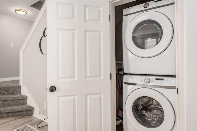 clothes washing area with stacked washer / dryer and light hardwood / wood-style flooring