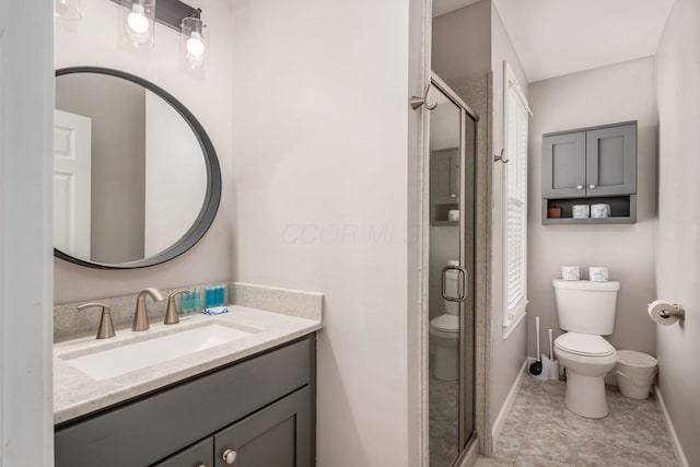 bathroom featuring vanity, a shower with shower door, and toilet