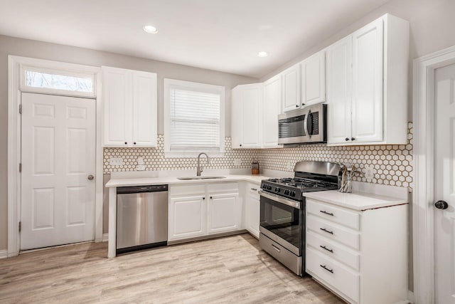 kitchen featuring sink, tasteful backsplash, light wood-type flooring, appliances with stainless steel finishes, and white cabinets