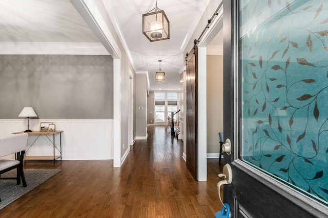 hallway featuring crown molding, a barn door, and dark wood-type flooring