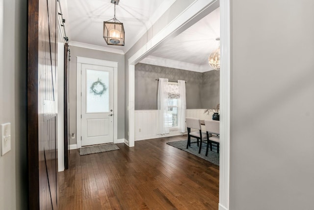 foyer entrance with dark hardwood / wood-style flooring, crown molding, and an inviting chandelier