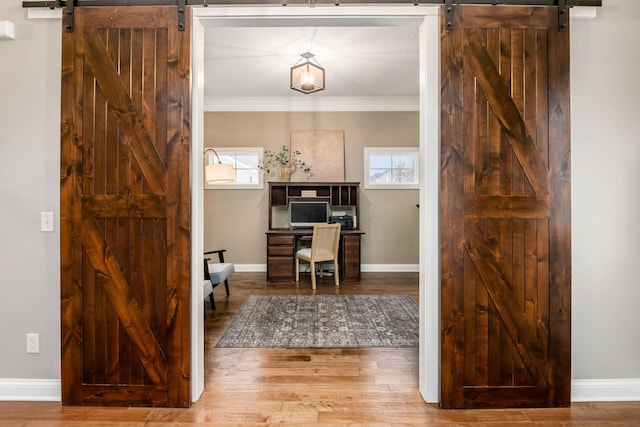 office area featuring hardwood / wood-style flooring, ornamental molding, and a barn door