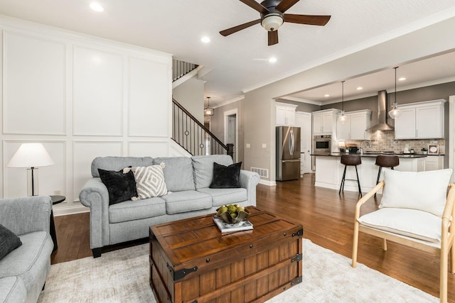 living room with crown molding, sink, ceiling fan, and light wood-type flooring