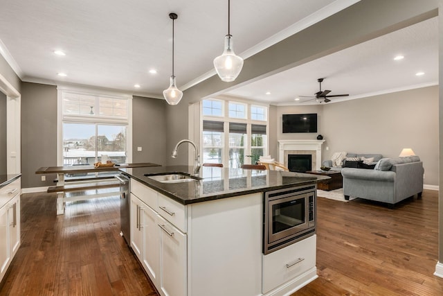 kitchen featuring white cabinetry, sink, pendant lighting, and stainless steel microwave