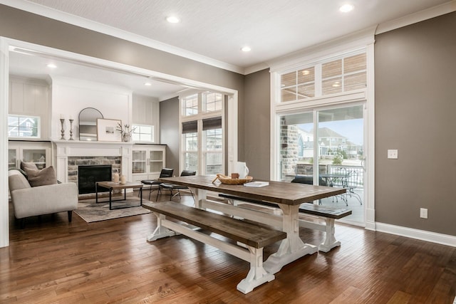 dining area featuring dark hardwood / wood-style flooring, a stone fireplace, and crown molding