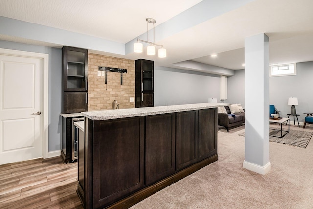 bar featuring pendant lighting, light colored carpet, and dark brown cabinets