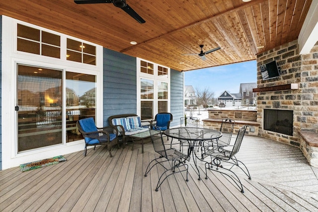 deck featuring ceiling fan and an outdoor stone fireplace