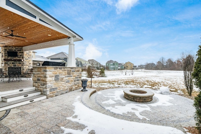 snow covered patio featuring ceiling fan and an outdoor fire pit