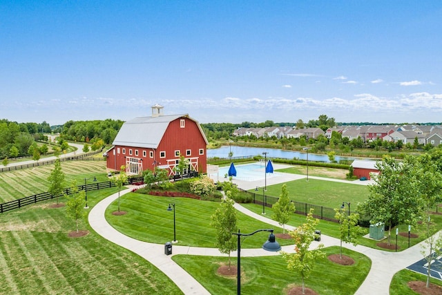 view of home's community with a water view, an outbuilding, and a lawn