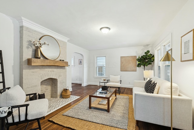 living room featuring a brick fireplace and dark wood-type flooring