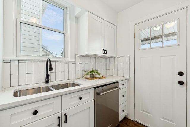 kitchen with tasteful backsplash, dishwasher, white cabinetry, sink, and light stone countertops