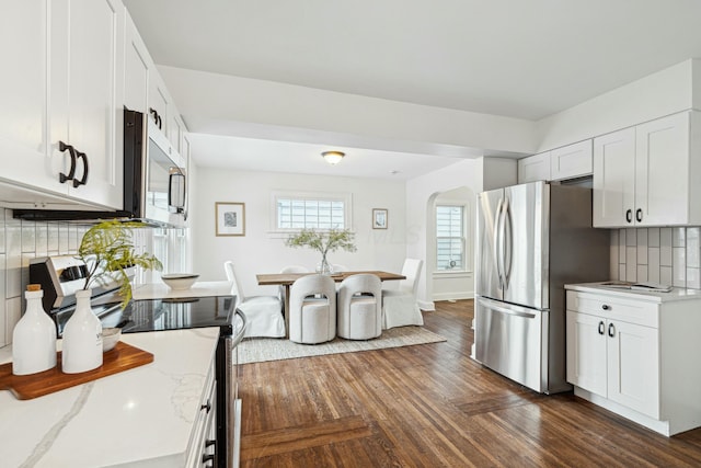 kitchen featuring light stone countertops, appliances with stainless steel finishes, white cabinets, and decorative backsplash