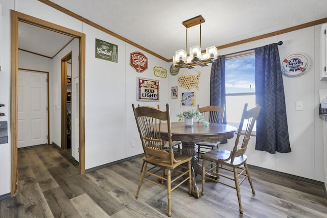 dining space featuring a notable chandelier, dark wood-type flooring, ornamental molding, and a textured ceiling